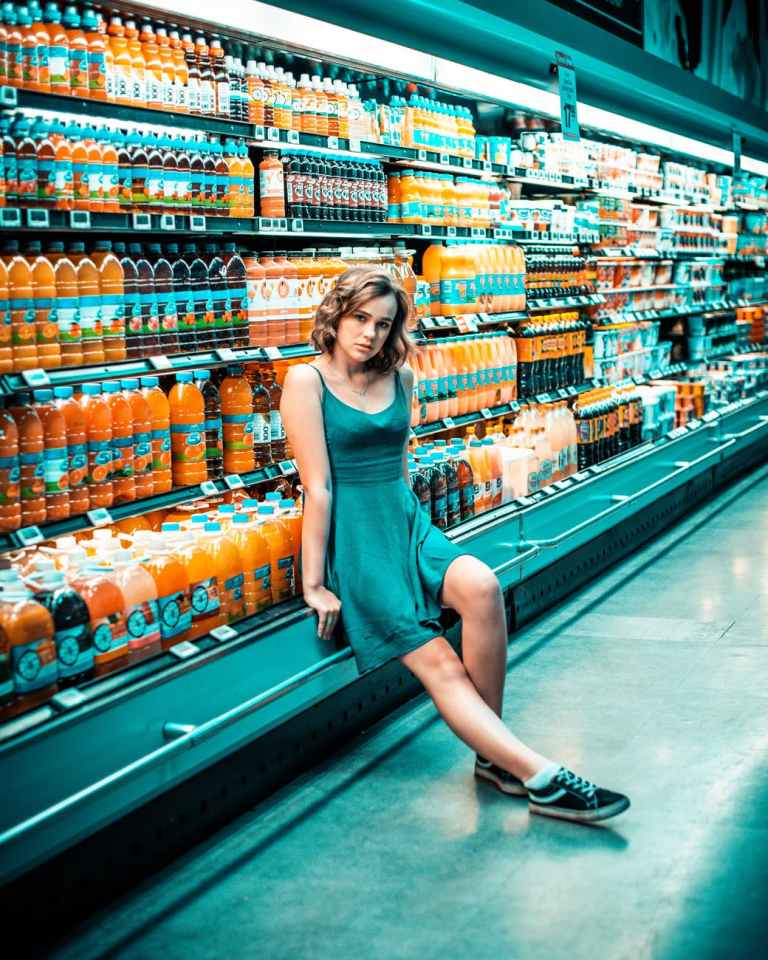 photo of woman sitting beside beverage section in grocery store